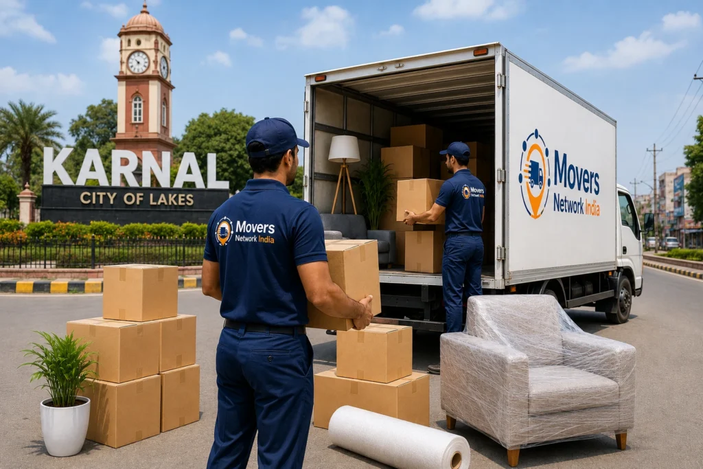 Packers and movers in Karnal loading household items into a Movers Network India truck near Karnal city landmark.