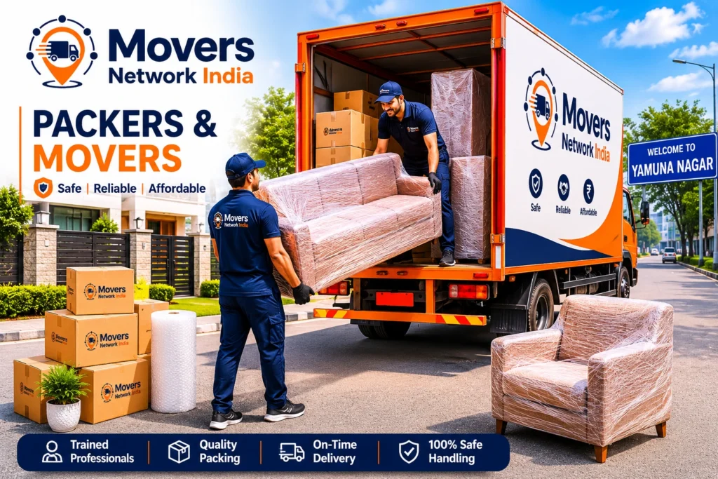 Packers and movers in Yamunanagar loading wrapped furniture and moving boxes into a branded relocation truck outside a residential house.